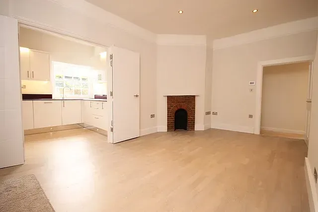 Una sala de estar vacía con una chimenea y una cocina al fondo.